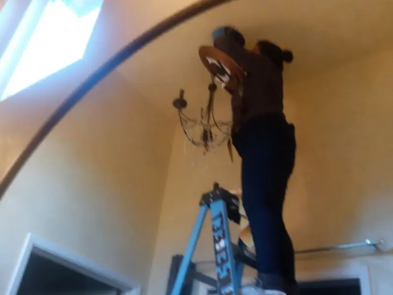 Electrician installing a chandelier in a Corry residence